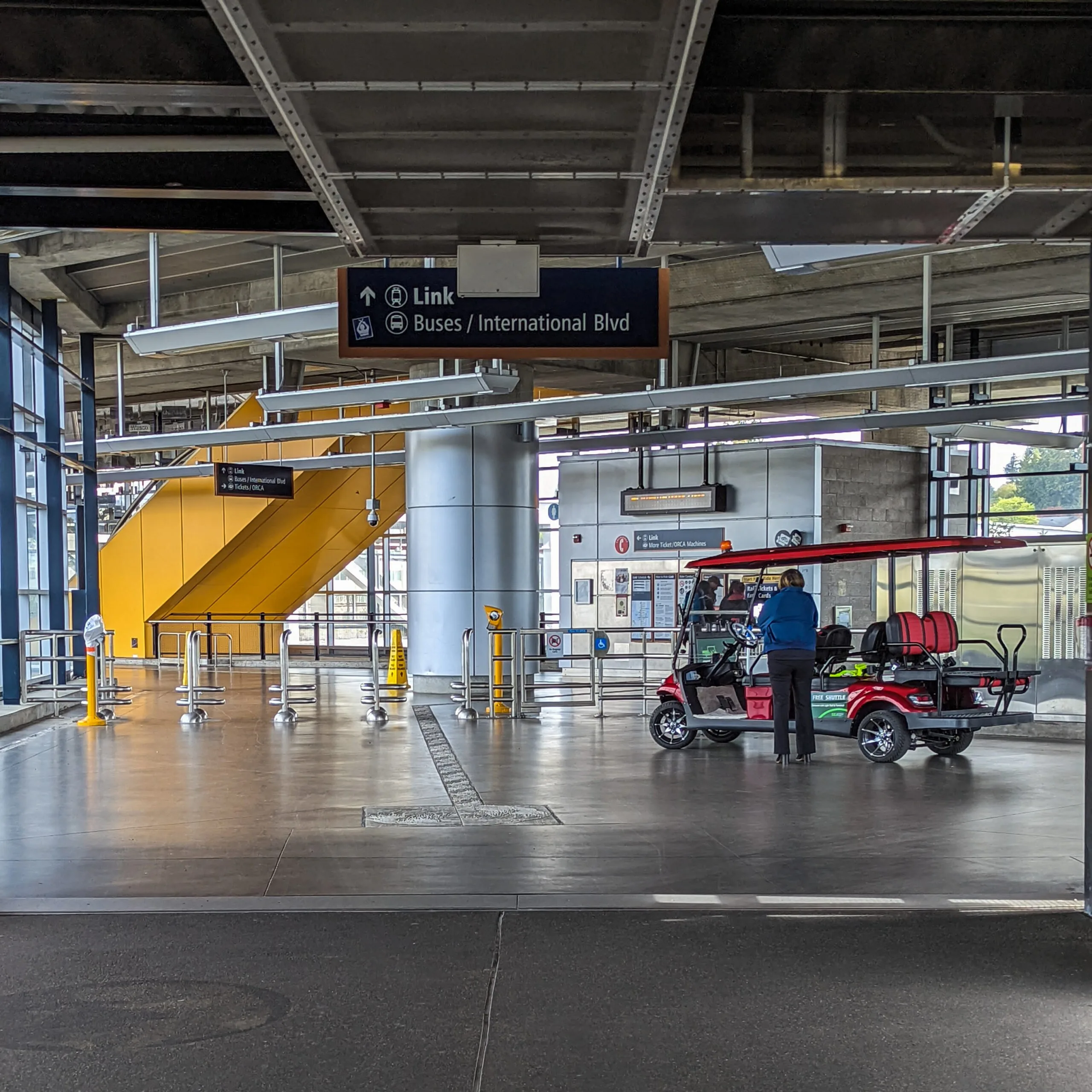 A shuttle operator stands at the entrance to the seatac light rail station.