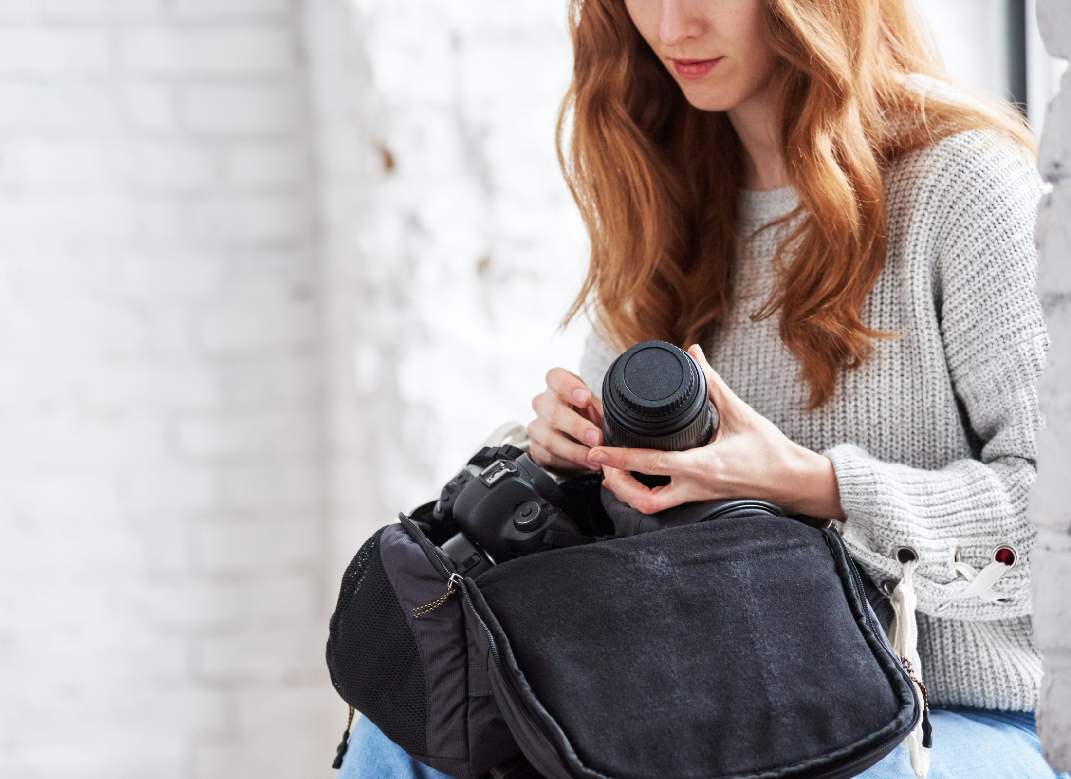 A woman holds a professional expensive camera and a travel camera bag