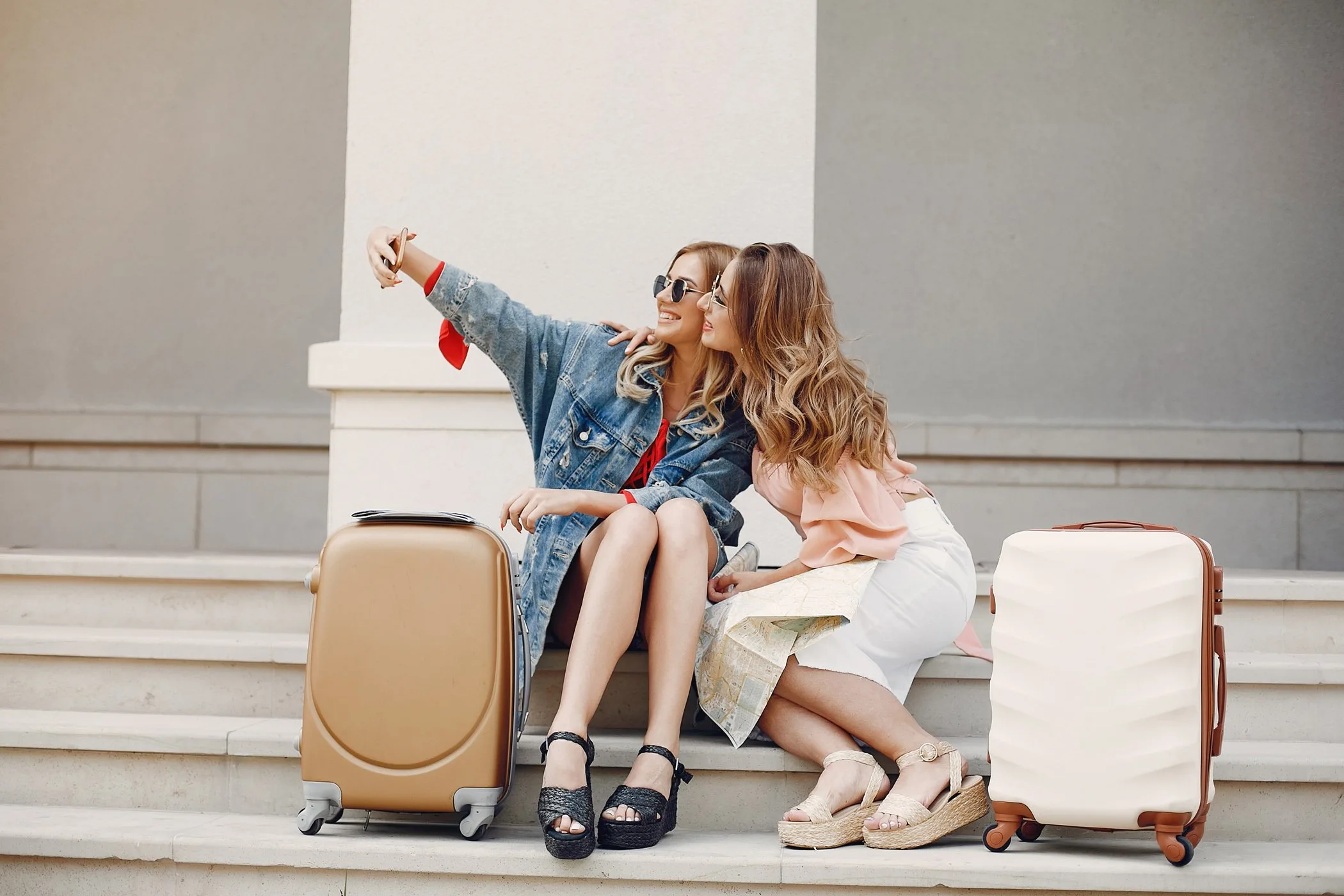 Two friends with luggage posing for a photograph.