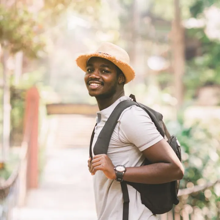 Male traveler standing on a bridge with smile.