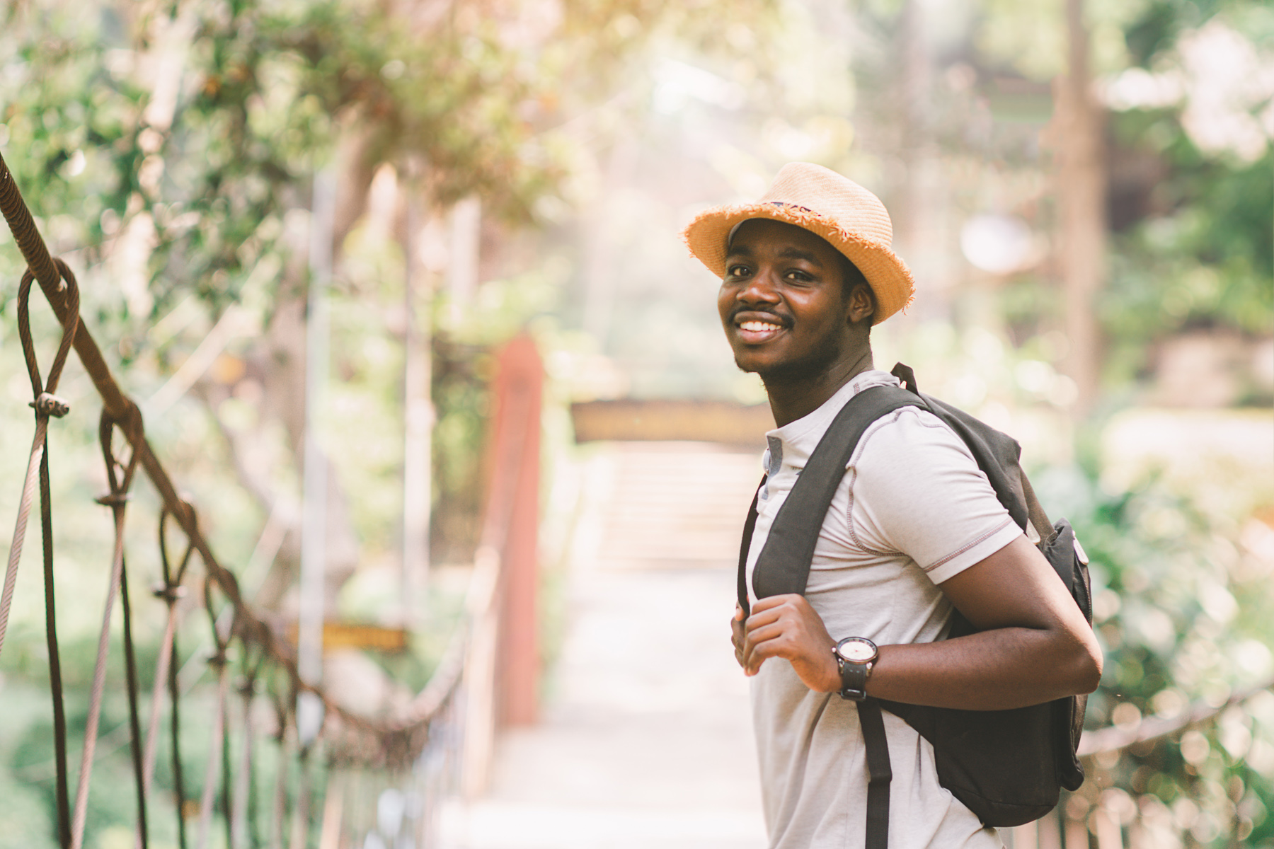 Male traveler standing on a bridge with smile in response to their first international trip.