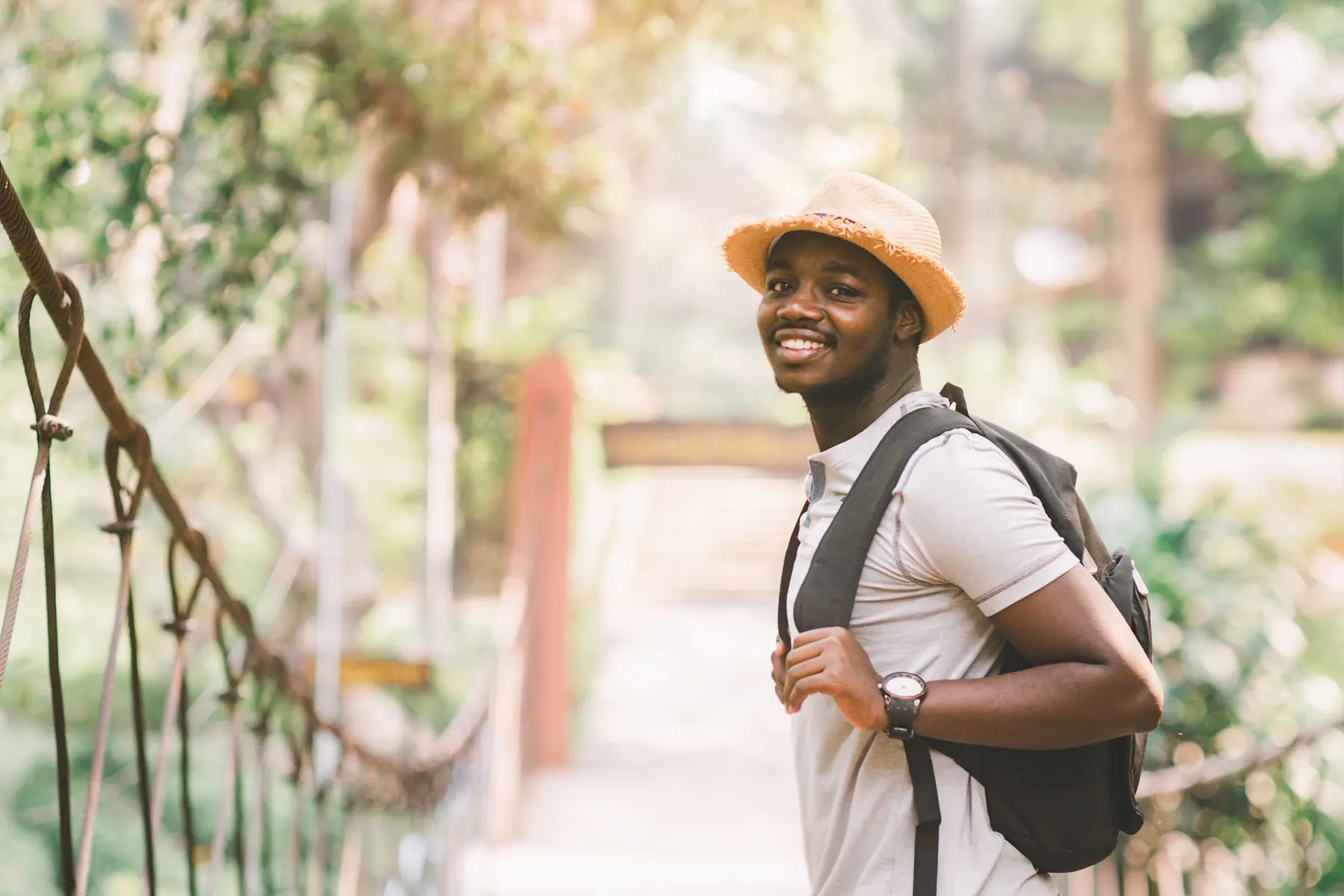 Male traveler standing on a bridge with smile in response to their first international trip.