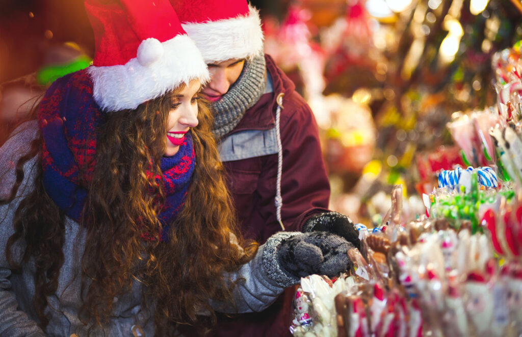 To travelers admire candy in a european christmas market.