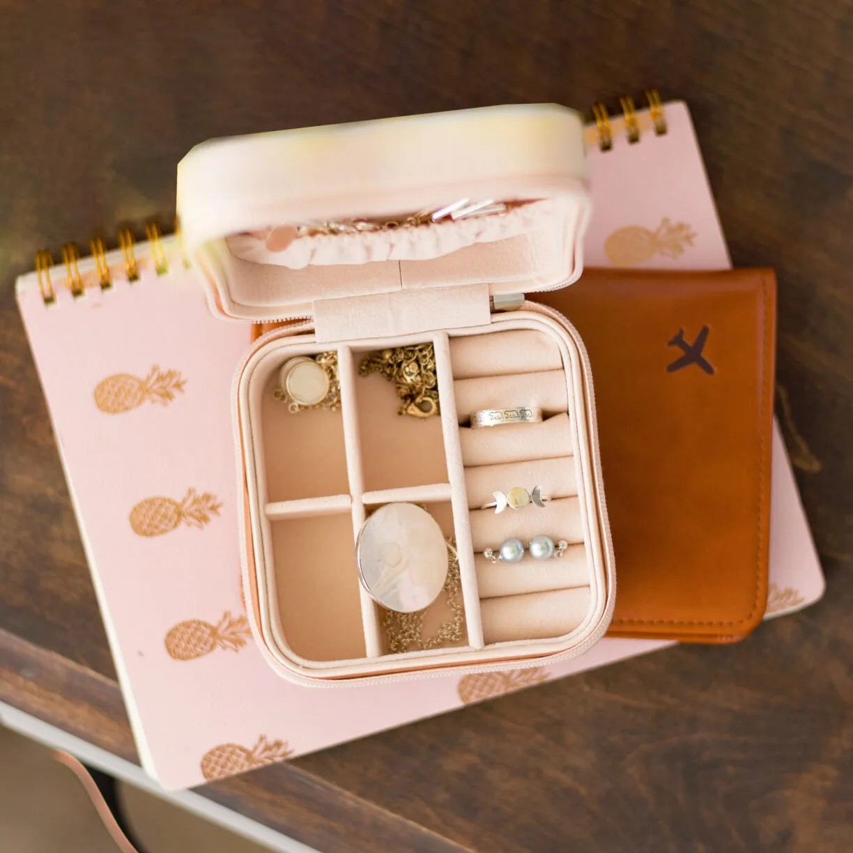 Jewelry case on top of a travel journal and a passport.