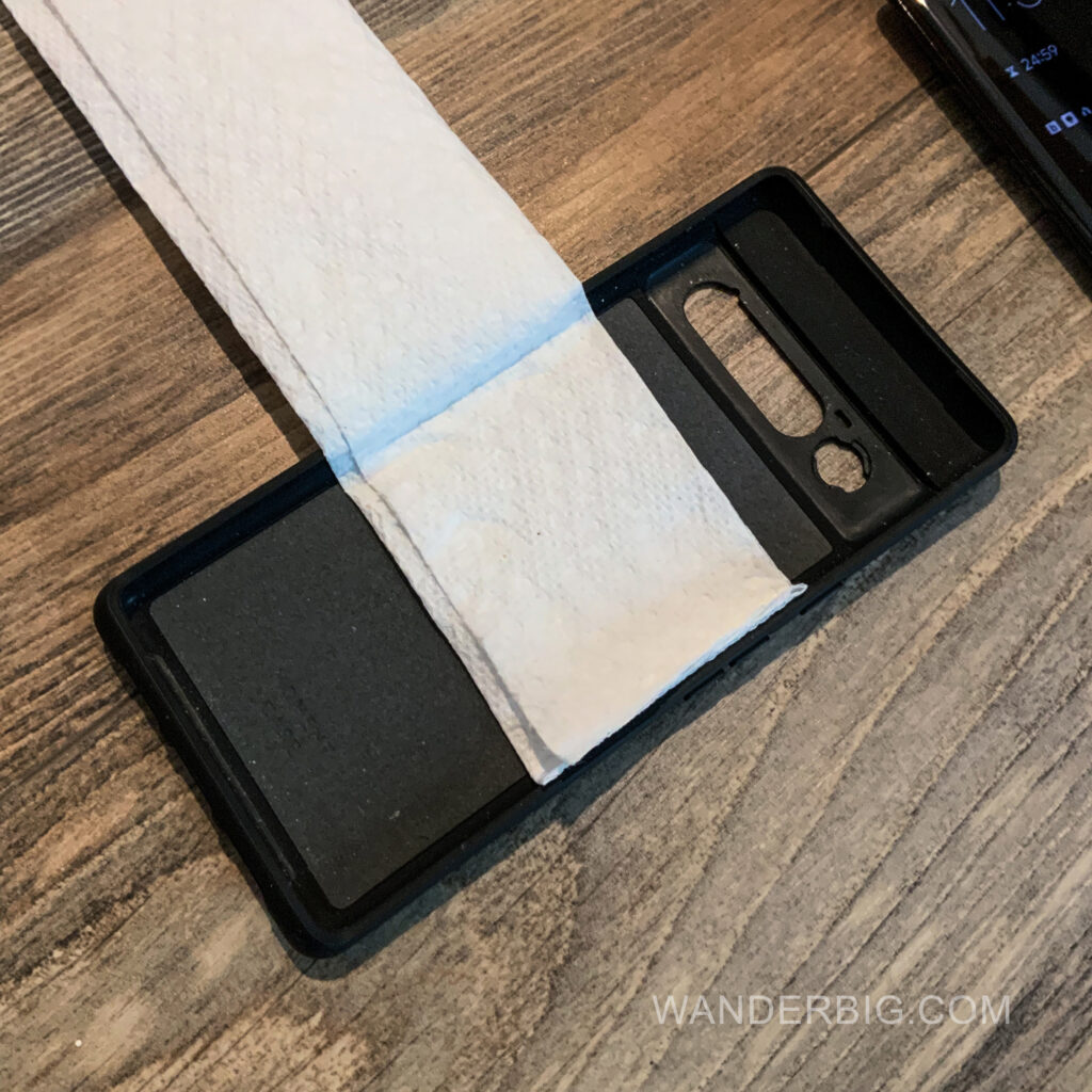 A paper towl in a cell phone case for mounting on the back of an airplane seat.