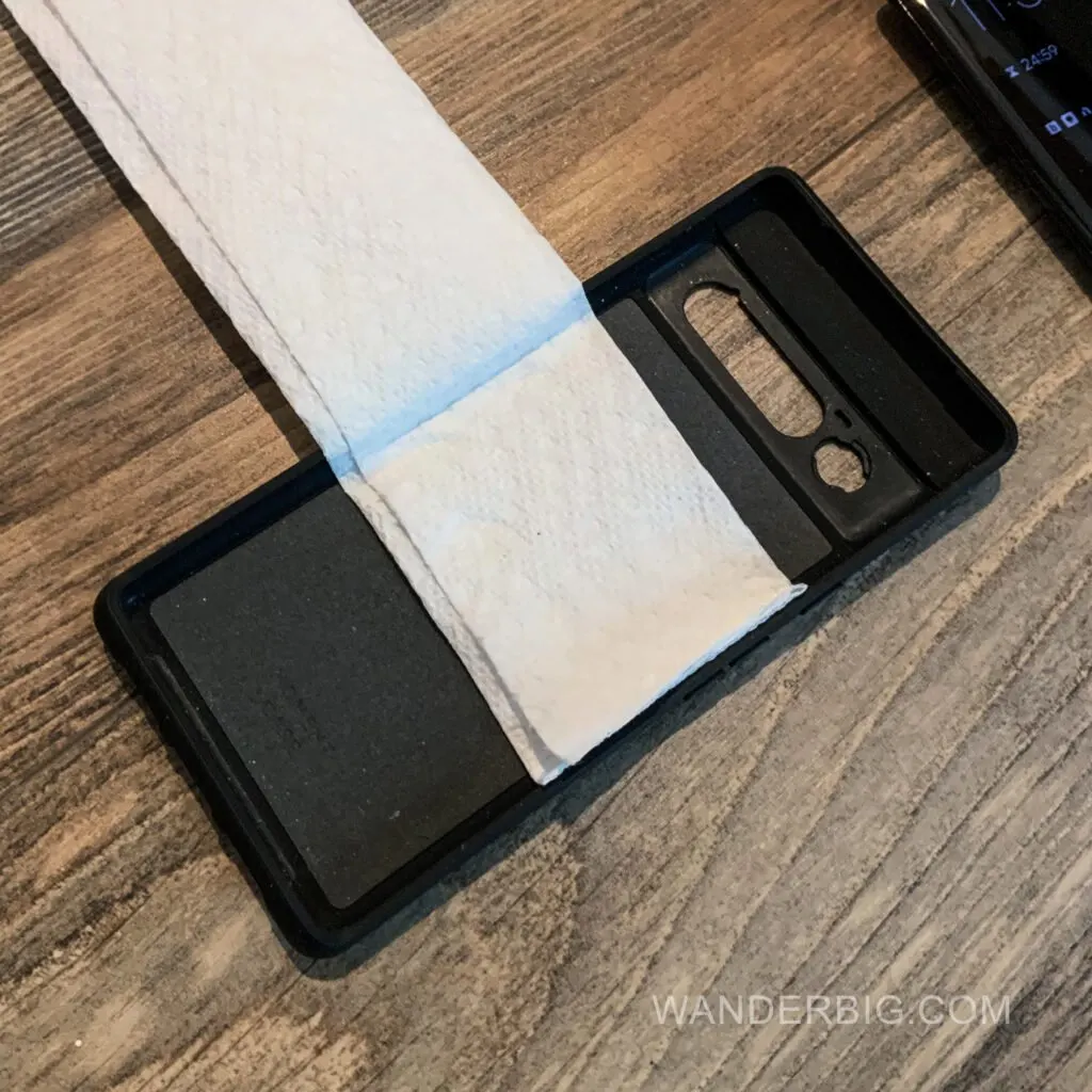 A paper towl in a cell phone case for mounting on the back of an airplane seat.