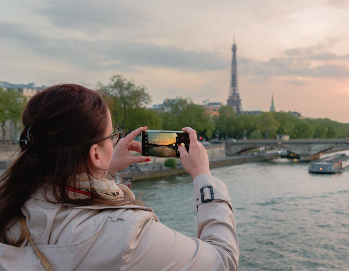 A woman taking a picture of the view near the eiffel tower in paris.