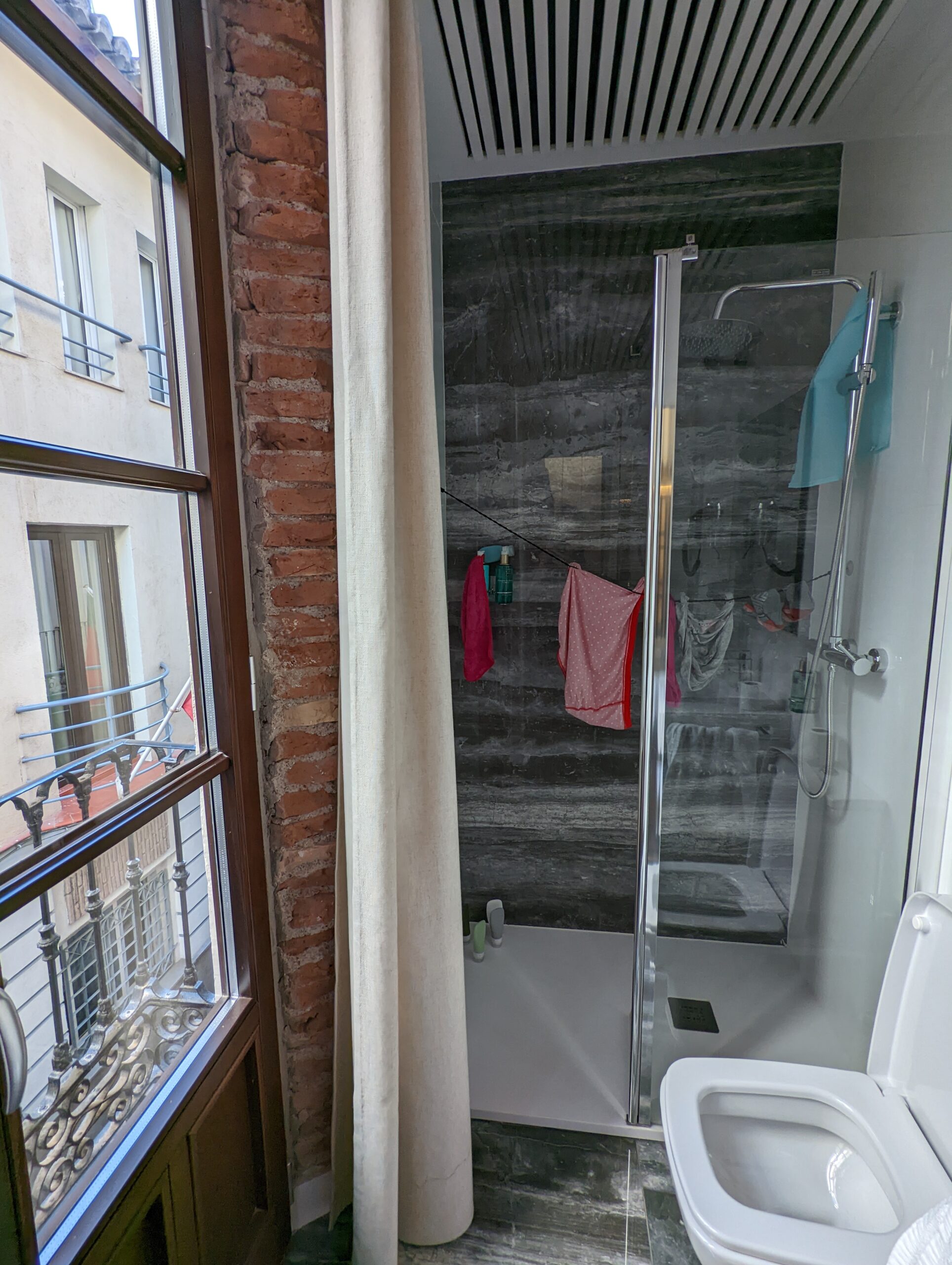 Clothing hanging on the clothesline in a shower to dry in the bathroom in a hotel