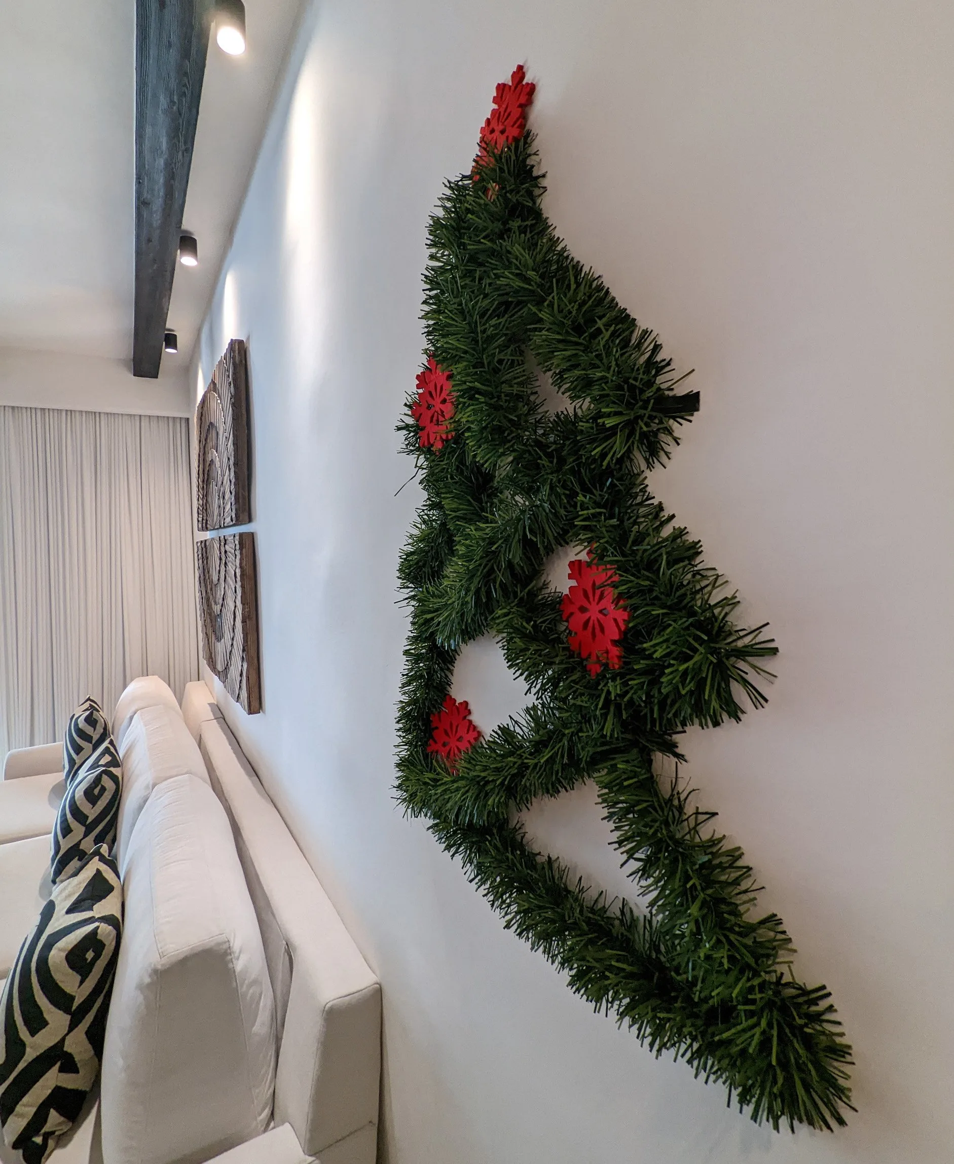 A hotel room decorated for christmas with a wall mounted diy garland christmas tree.