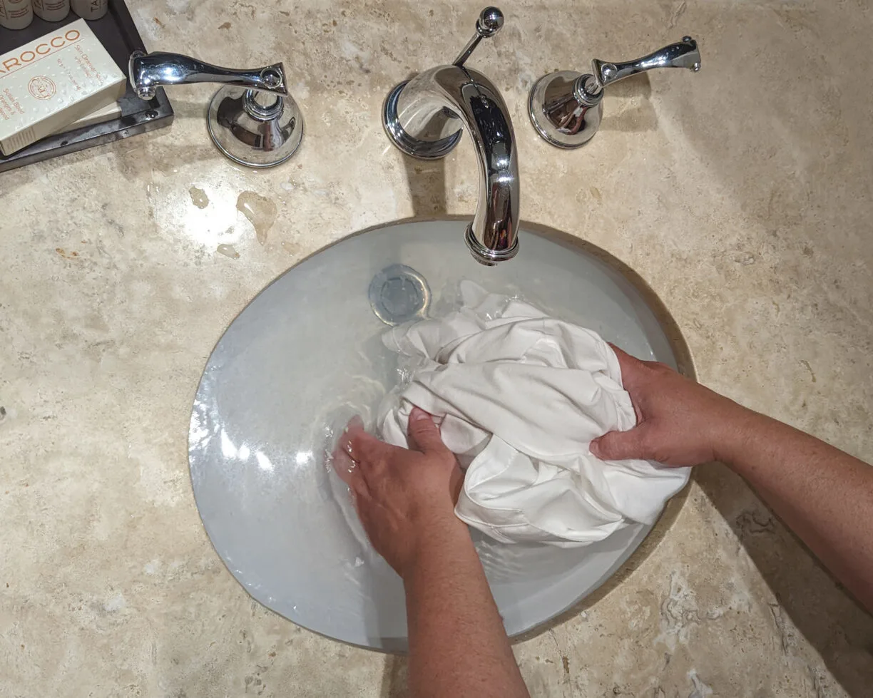 Grating soap into a hotel sink for washing clothes