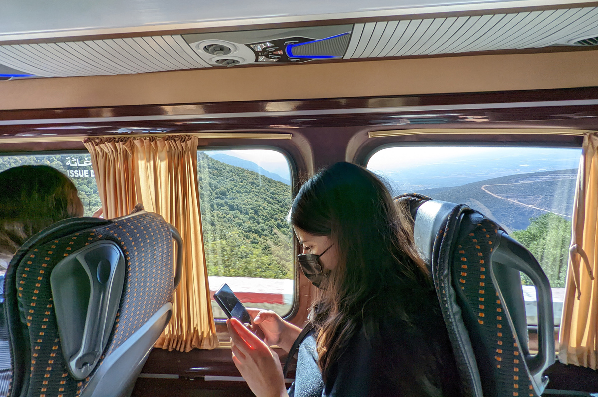 A woman looks at her phone while riding in a group tour van in morocco.