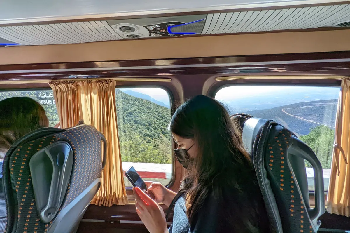A woman looks at her phone while riding in a group tour van in morocco.