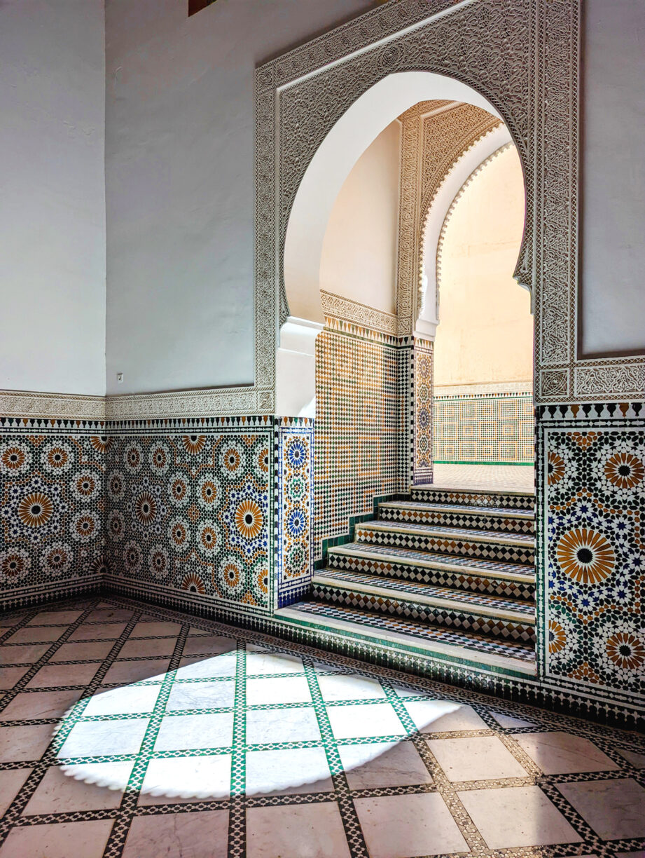 A keyhole -shaped door in the mosque in morocco, surrounded by hand cut tiles.