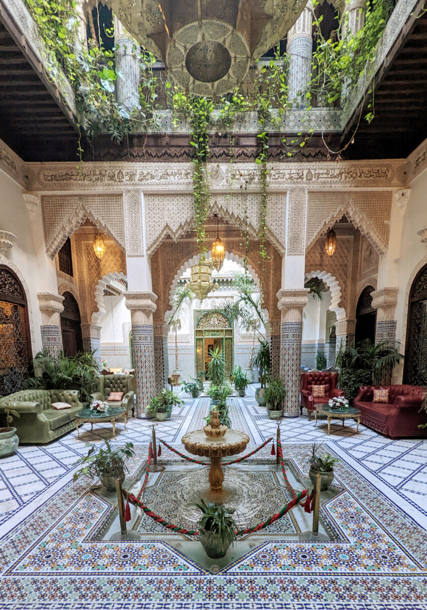 The inside of a moroccan riad, courtyard with plants and fountains.