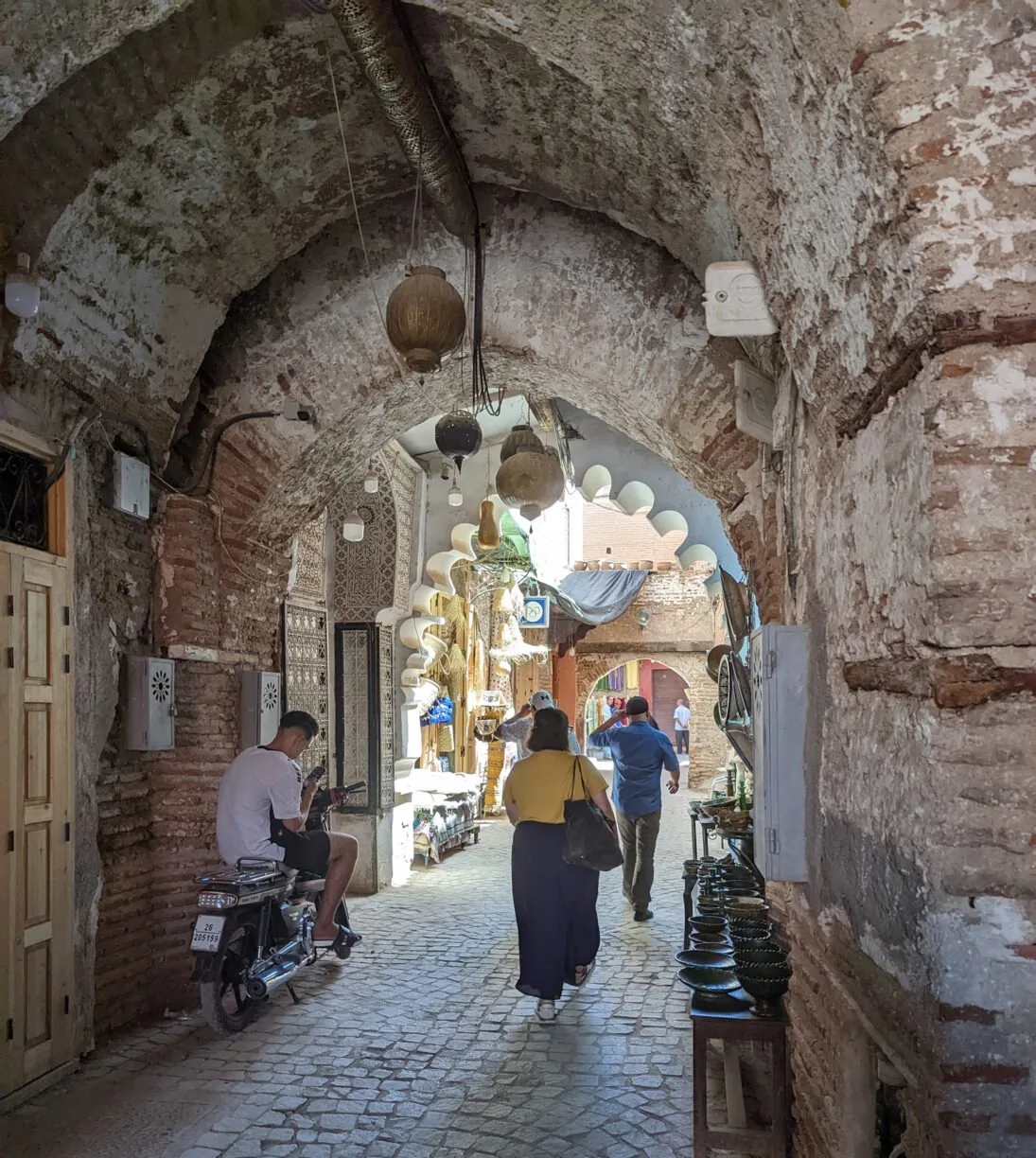 Tourists walk through an ancient walkway in the medina in marrakesh morocco.