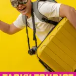 Man wearing tacky tourist costumes including tshirt, camera, and suitcase.