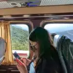 A woman looks at her phone while riding in a group tour van in morocco.