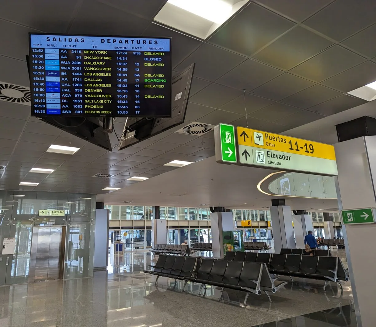 Airport view showing arrivals and departures screen and a boarding gate.