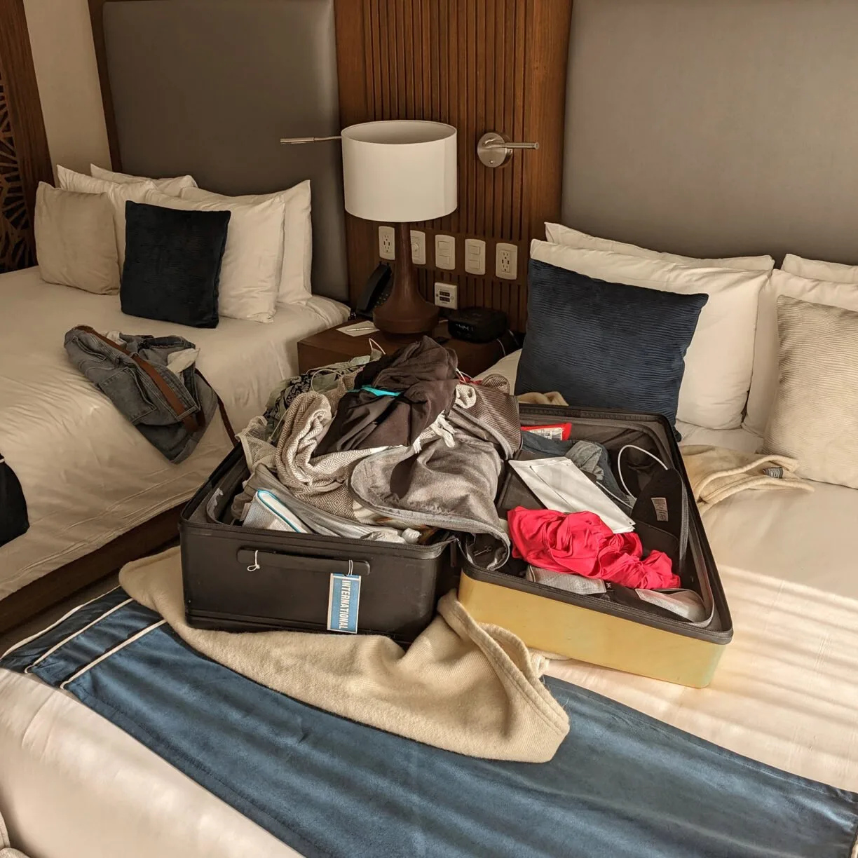An overflowing suitcase packed with messy unfolded clothing.