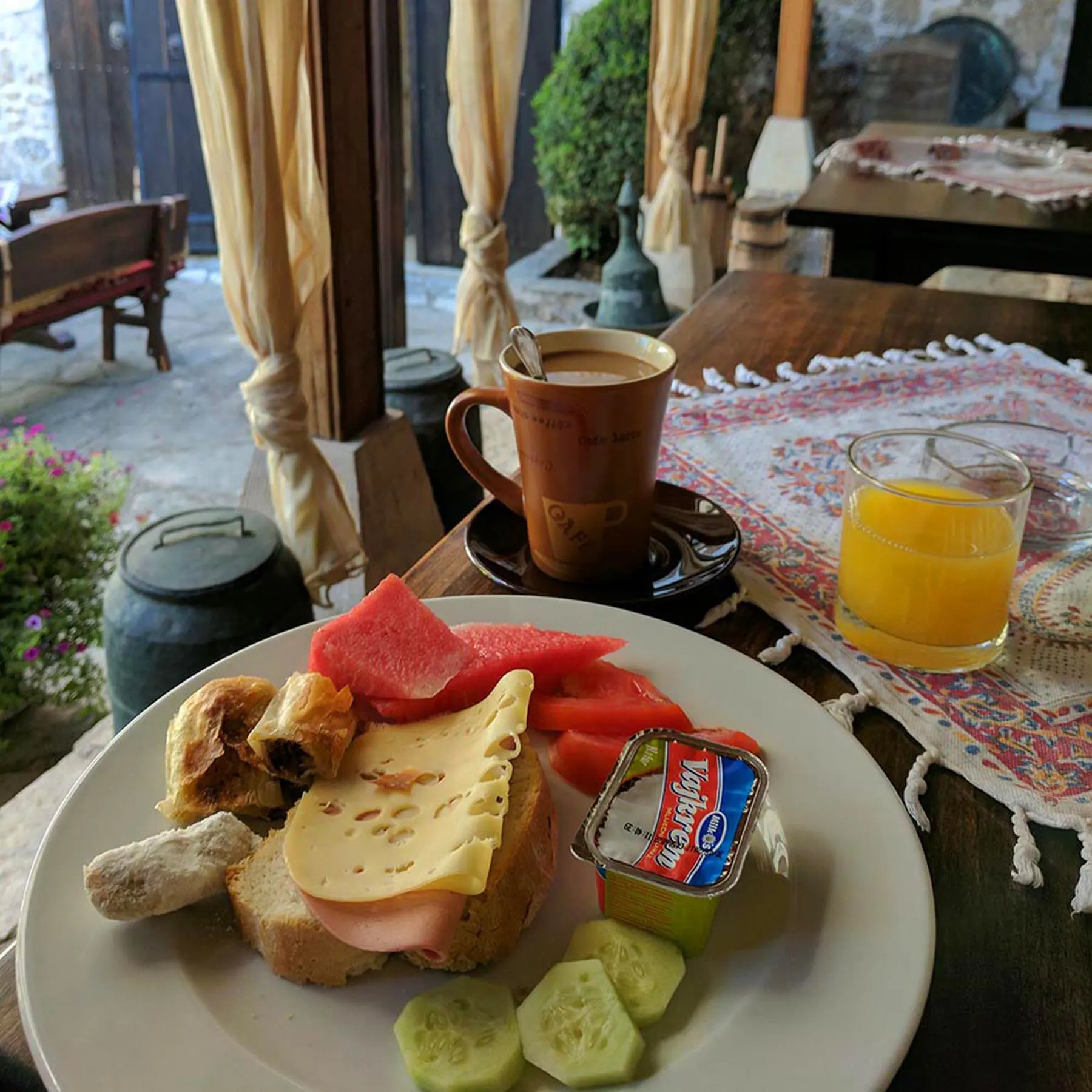 A table in a restaurant in bosnia with breakfast food and a table setting for one person.