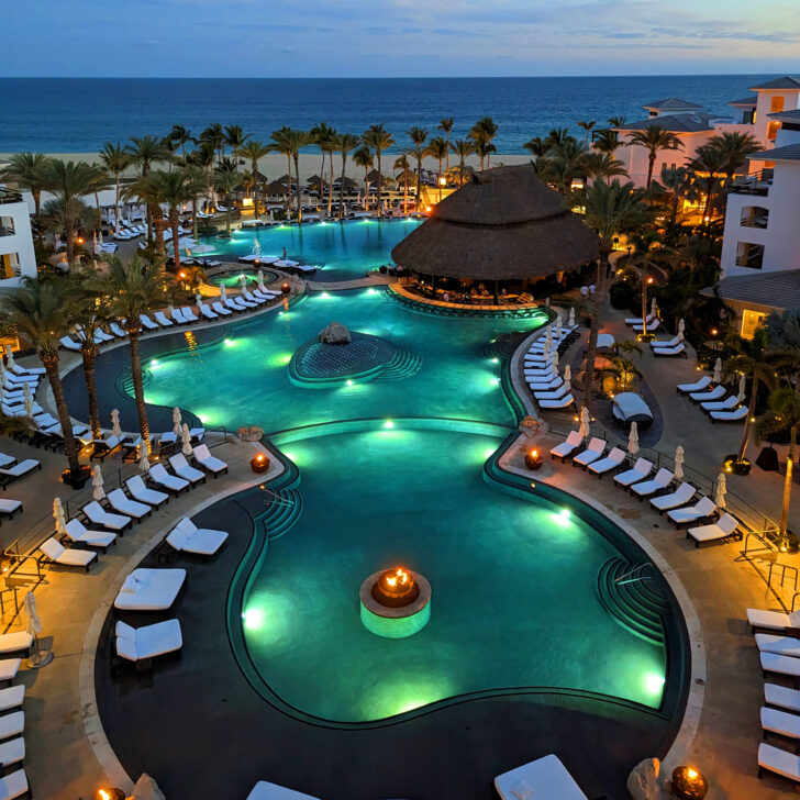 The pools of a all inclusive resort lit up before sunrise.