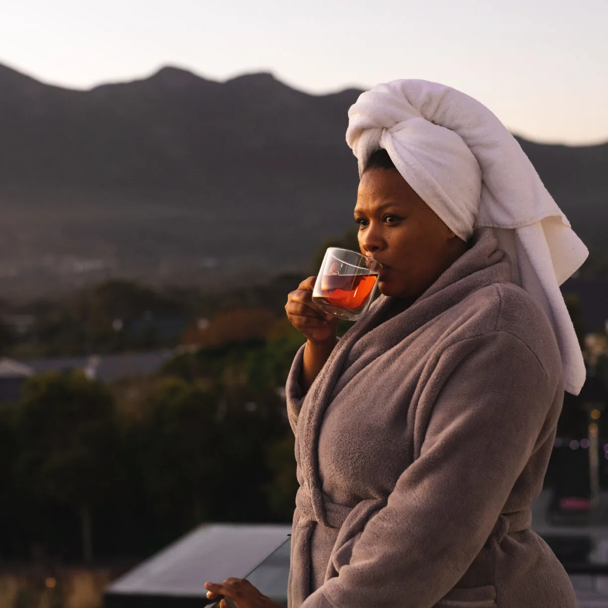 Woman in a robe sipping a cup of tea.