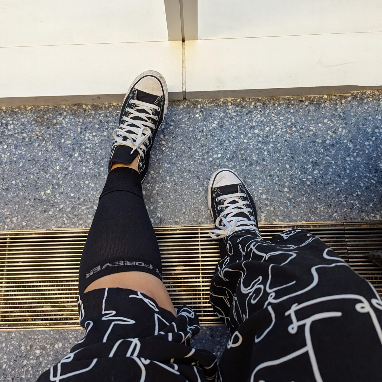 A plus size traveler ready for a long flight with compression socks and loosely tied sneakers.