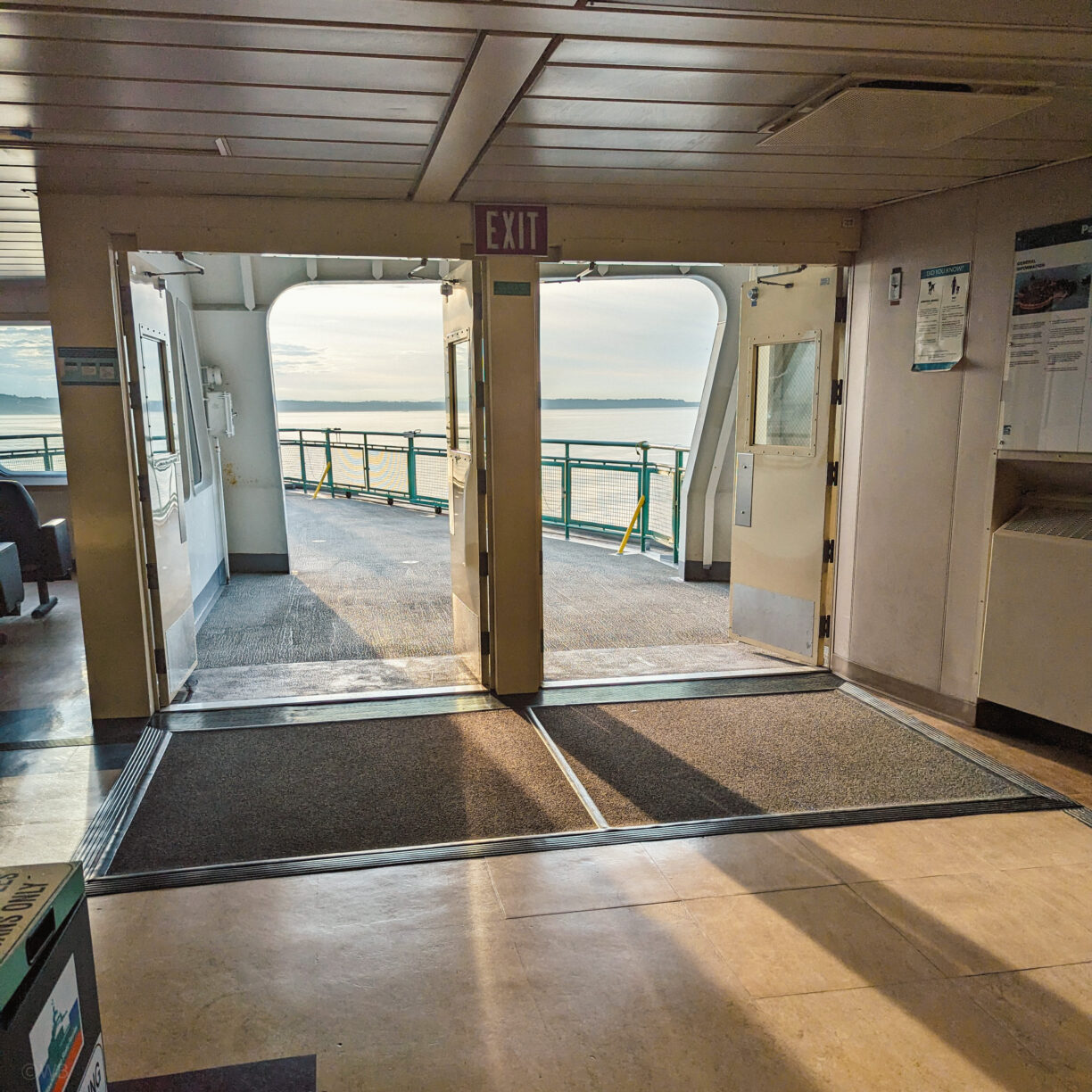 A view of the outside of a washington state ferry deck as from the interior seating area.
